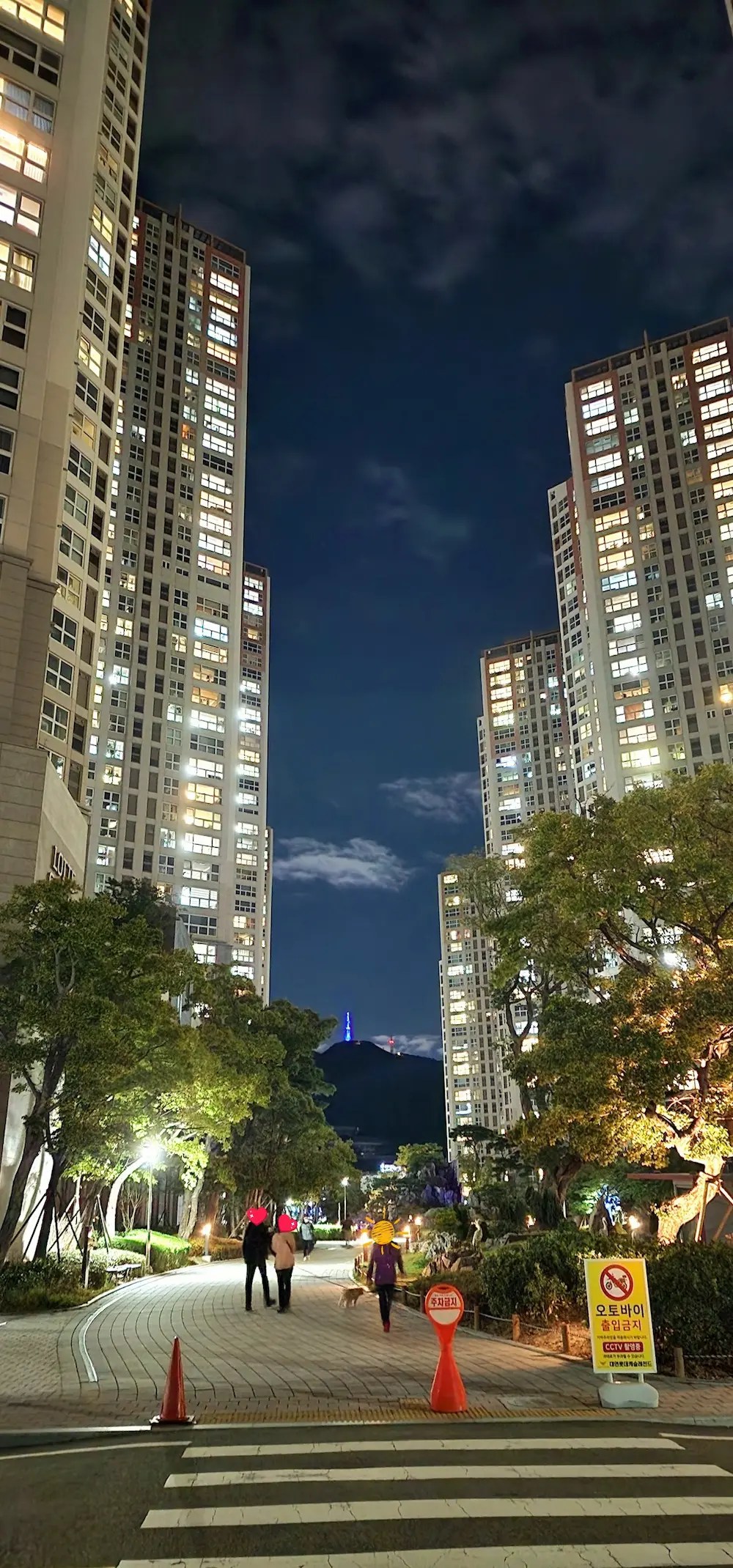 Night view of apartment complex near Cafe Magnate in Busan, with people walking through the central plaza