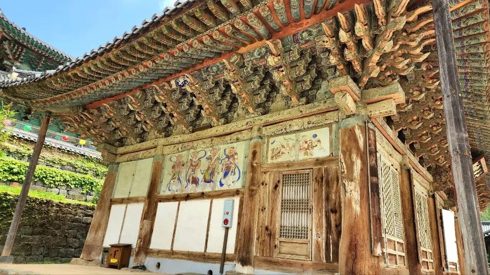 A traditional wooden hall at Magoksa Temple in Gongju, South Korea, featuring dancheong-painted eaves and Buddhist wall paintings.