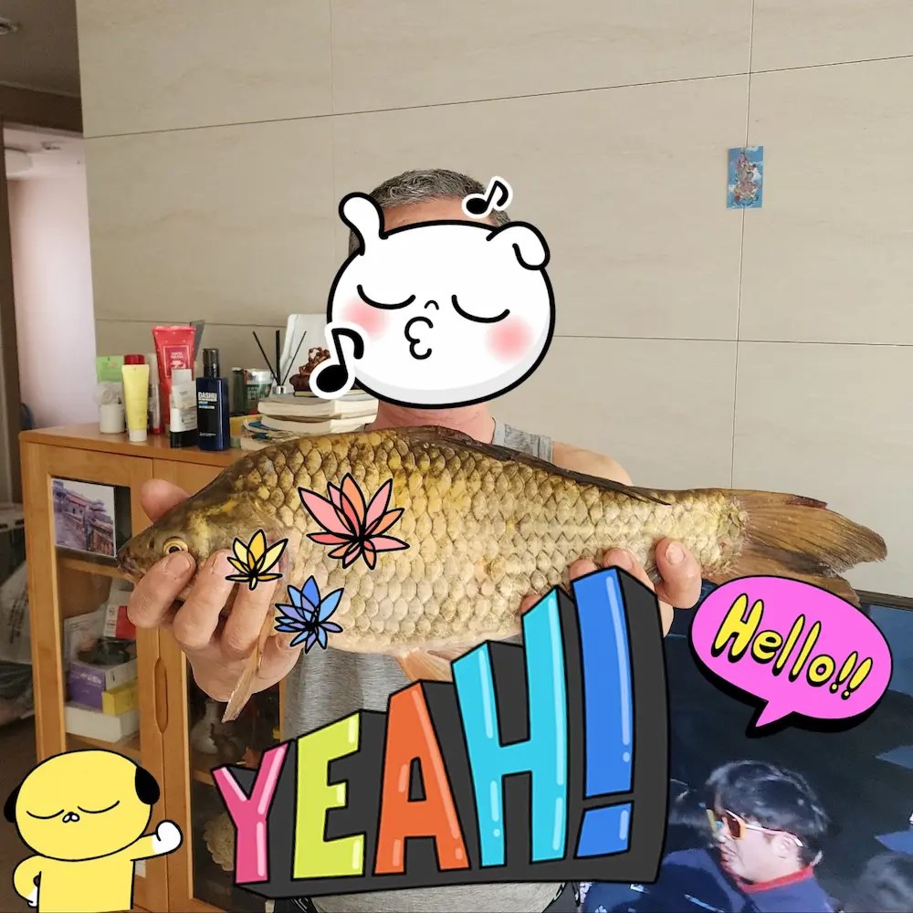 A man smiling while holding a freshly caught crucian carp after fishing.