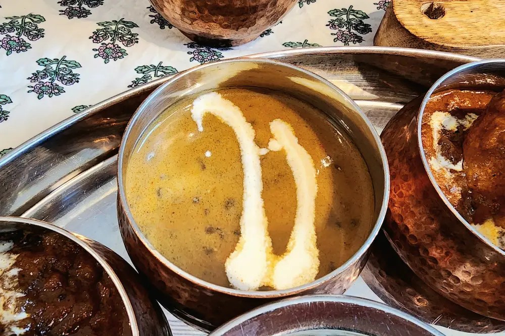 A close-up of dal makhani, a rich Indian lentil curry topped with two streaks of cream