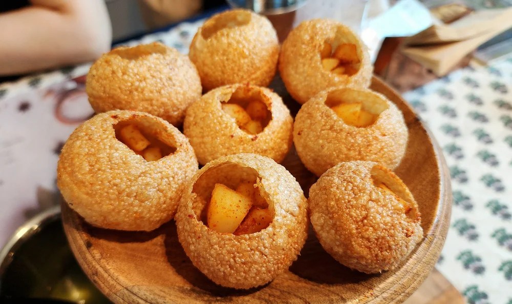 Plusieurs panipuris dorés alignés sur une assiette