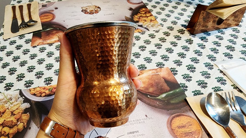 Gobelet martelé de style indien en cuivre, tenu à la main