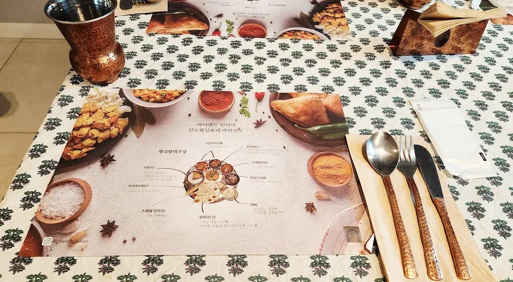 Copper cutlery, royal thali placemat, and table setting at Bhavan Indian restaurant in Busan