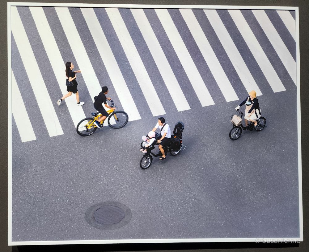 Cyclistes et piétons traversant un passage piéton large, vus du dessus