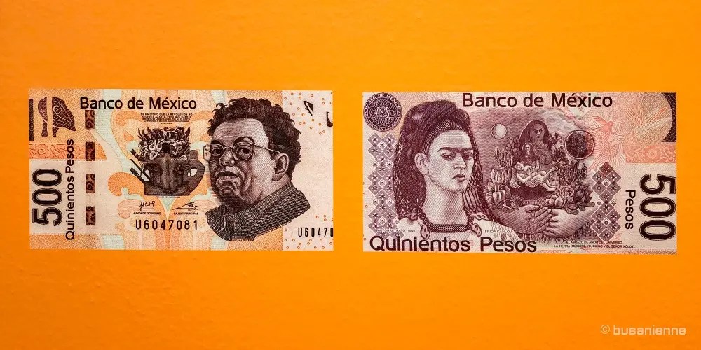Two enlarged images of the Mexican 500 Peso banknote against an orange background, showing Diego Rivera on the left and Frida Kahlo on the right. / Deux images agrandies du billet de banque mexicain de 500 Pesos sur fond orange, montrant Diego Rivera à gauche et Frida Kahlo à droite.