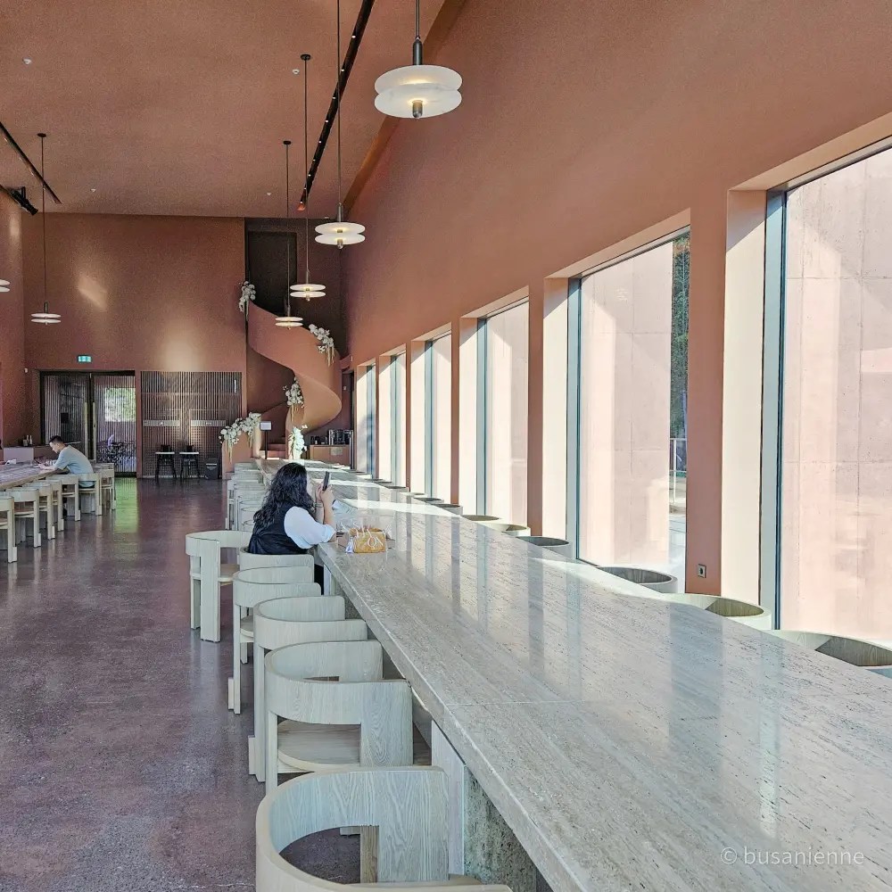 Café interior with marble counter, wooden stools, and terracotta walls at Sihaon Café in Ulsan.