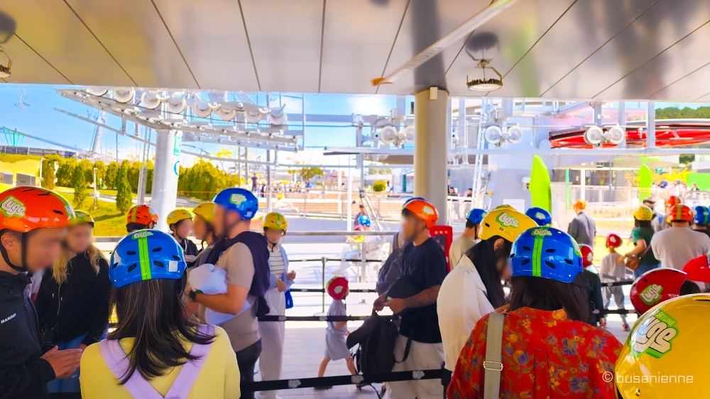 Crowd of visitors wearing helmets waiting in the Skyride queue at Skyline Luge Busan.